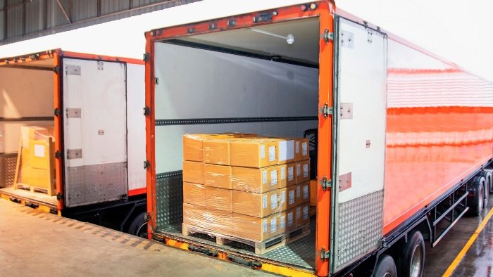 Palletised cartons arranged inside open transport trailers